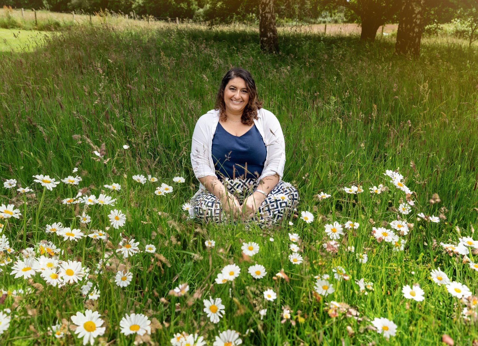 Louiza Leneghan, founder of Empowering Minds, sitting in a field of daisies, smiling warmly.