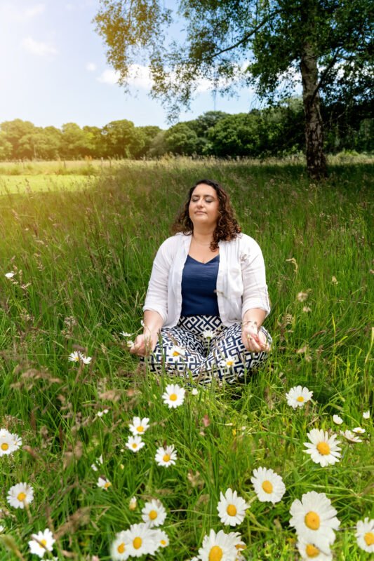 Louiza Leneghan meditating in a field of daisies, embodying peace and mindfulness.