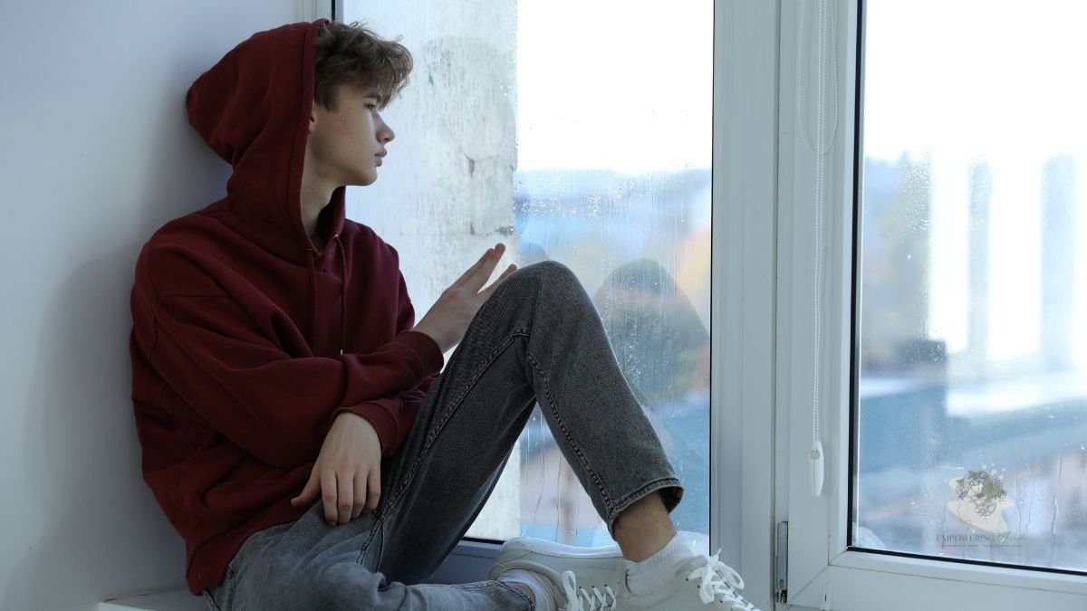 Teenager sitting quietly by a window at home