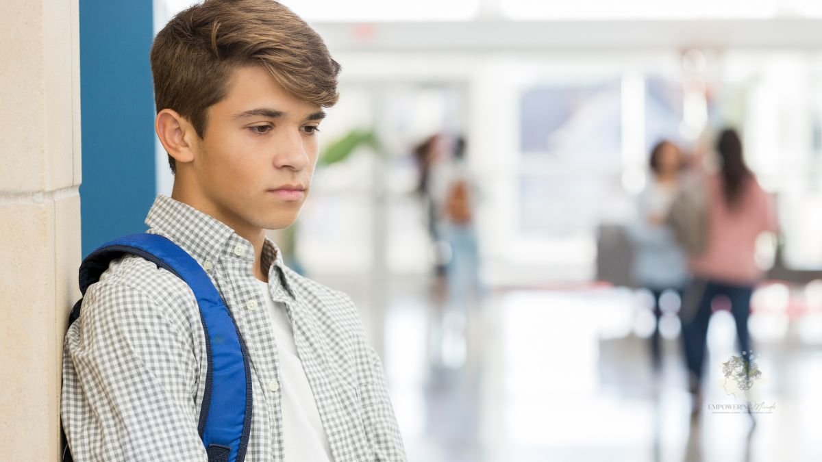 Teenager standing alone in a school corridor looking overwhelmed
